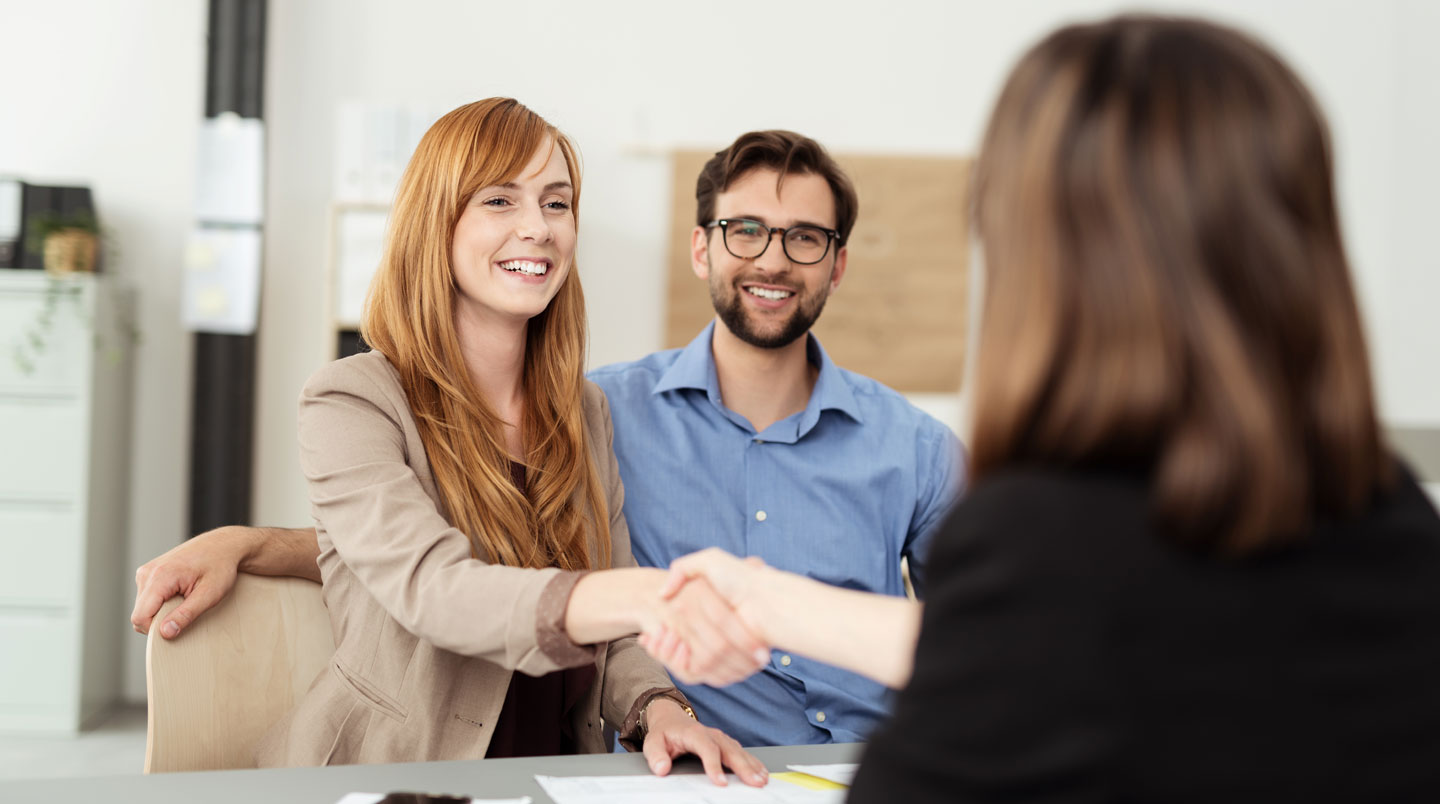 Conseiller bancaire français présentant sur écran une simulation de rachat de crédit immobilier à un client quadragénaire